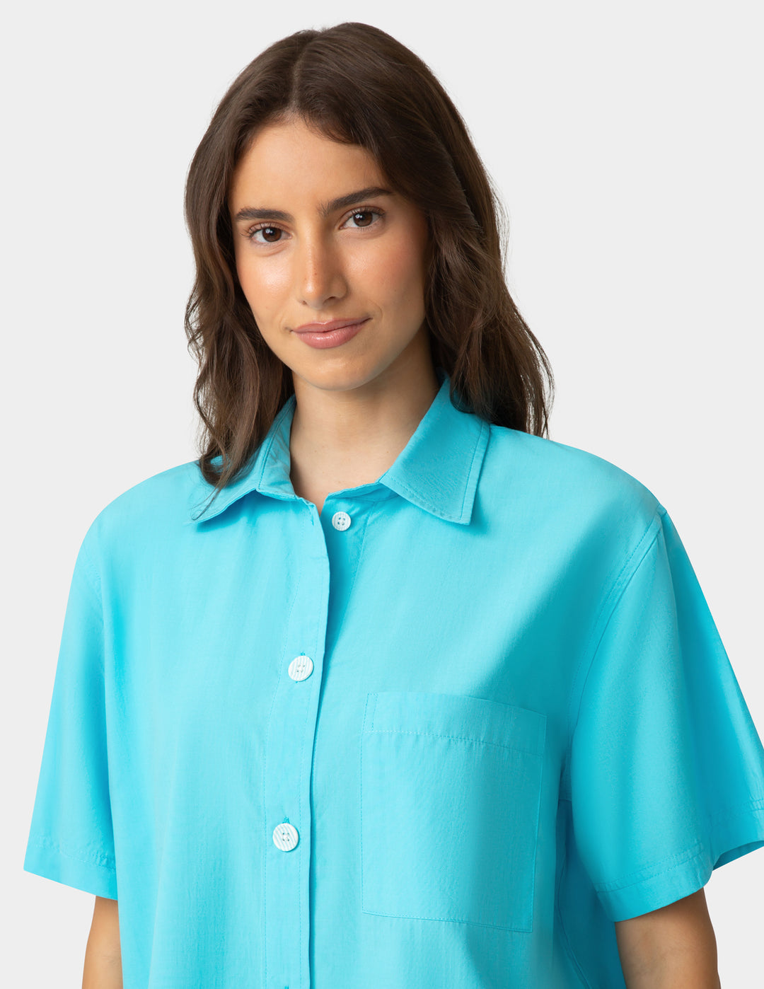 Woman wearing a turquoise shirt against a plain background