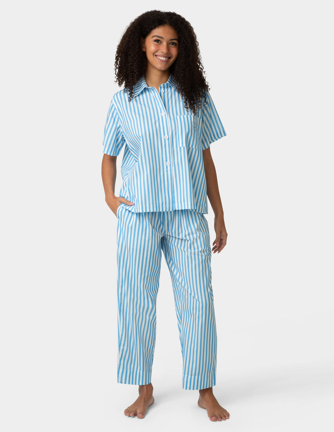 Woman wearing a blue and white striped pajama set on a white background