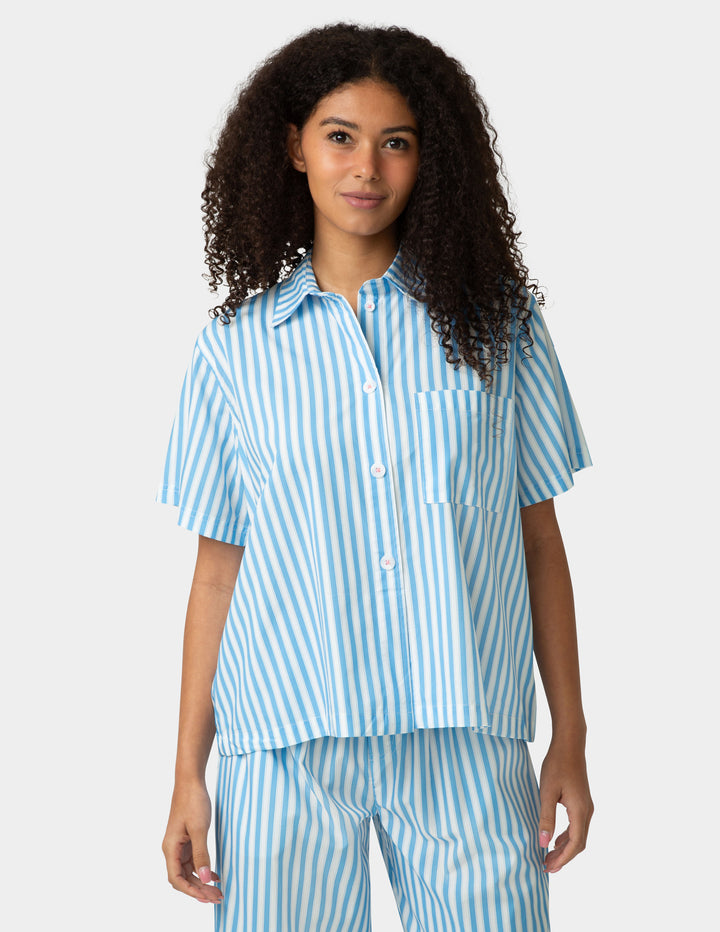 Woman wearing a blue and white striped pajama set on a white background