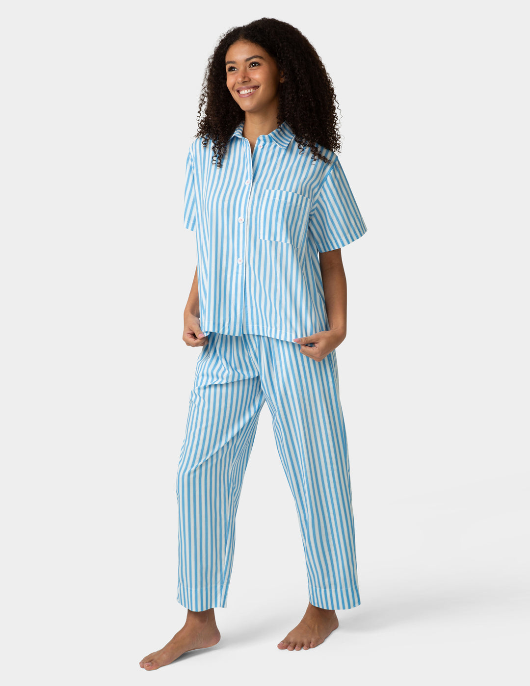 Woman wearing a blue and white striped pajama set on a white background