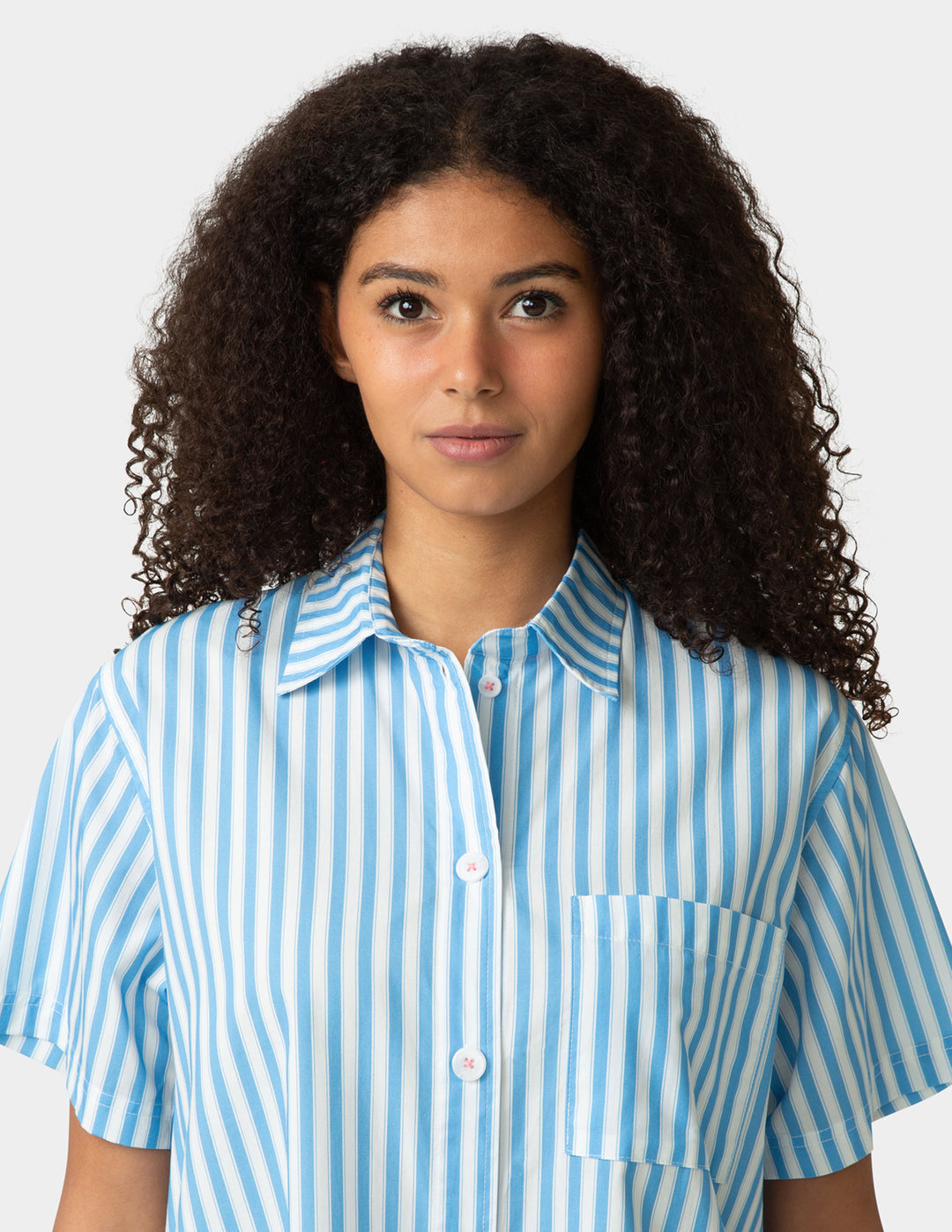 Woman wearing a blue and white striped shirt against a plain background