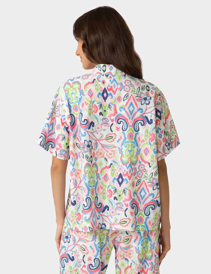 Woman wearing a colorful patterned shirt on a white background