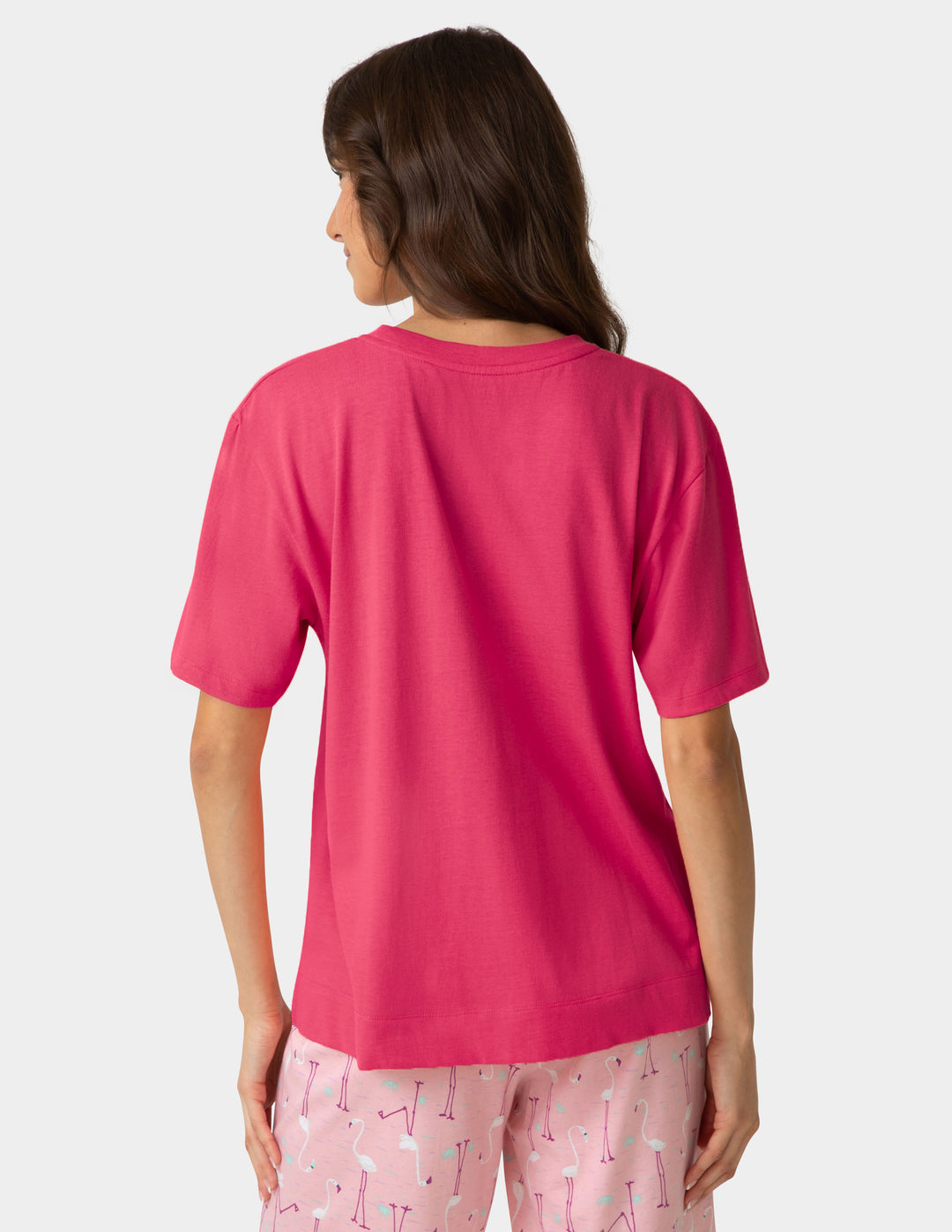 Woman wearing a pink pajama t-shirt and pajama pants on a white background