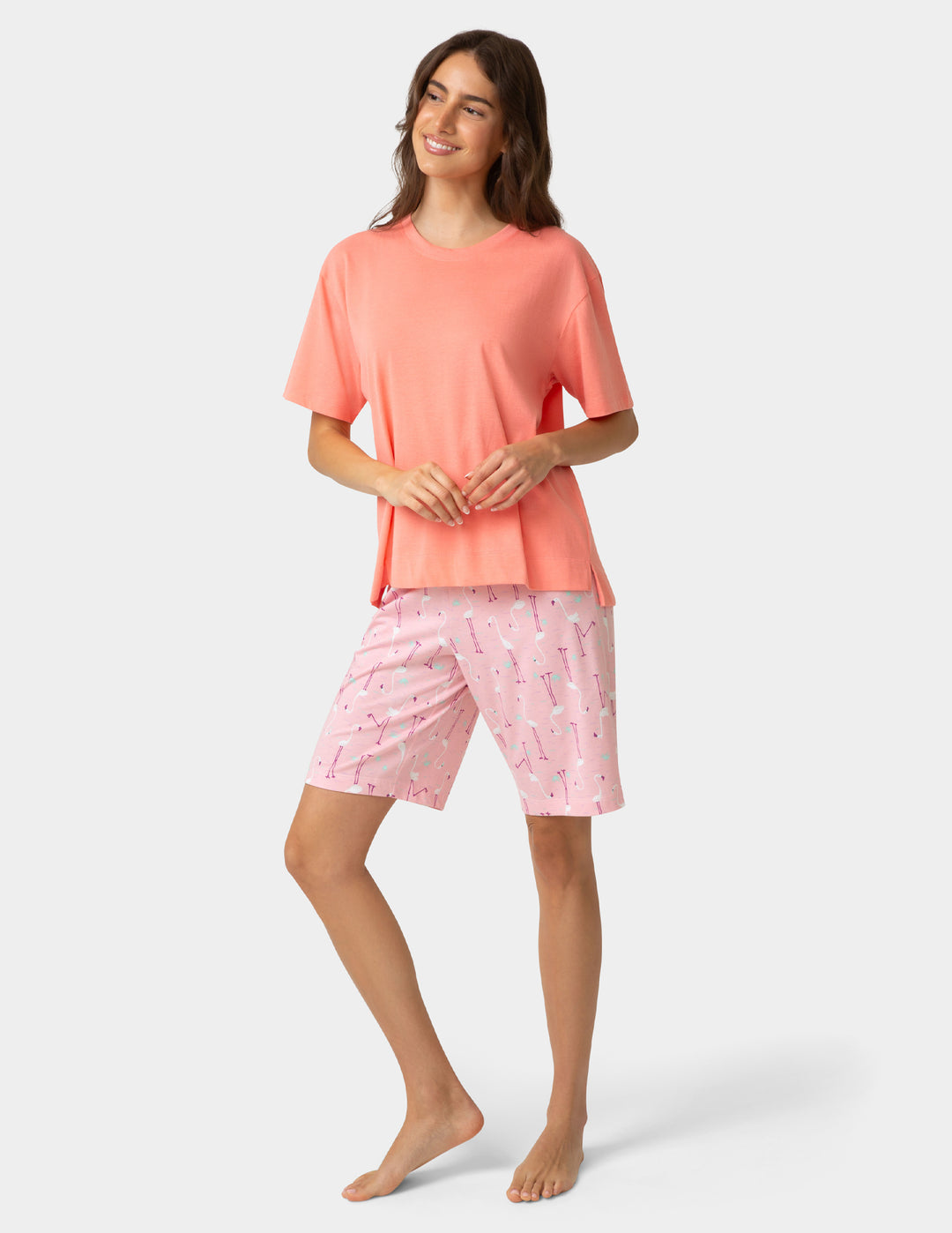 Woman wearing a coral top and pink shorts with a subtle pattern on a white background