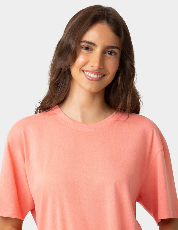 Woman wearing a coral-colored shirt against a plain background