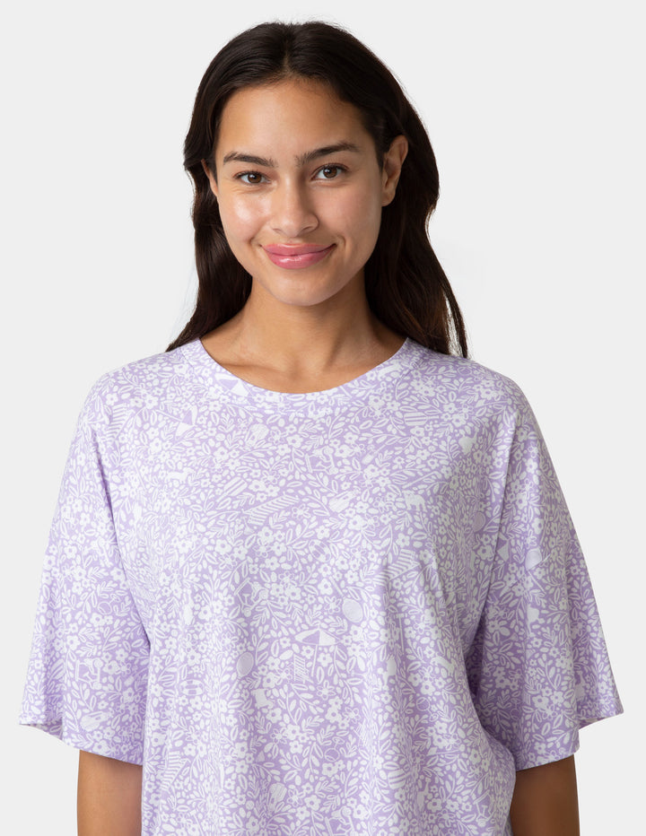 Woman wearing a light purple t-shirt with a subtle pattern on a plain background