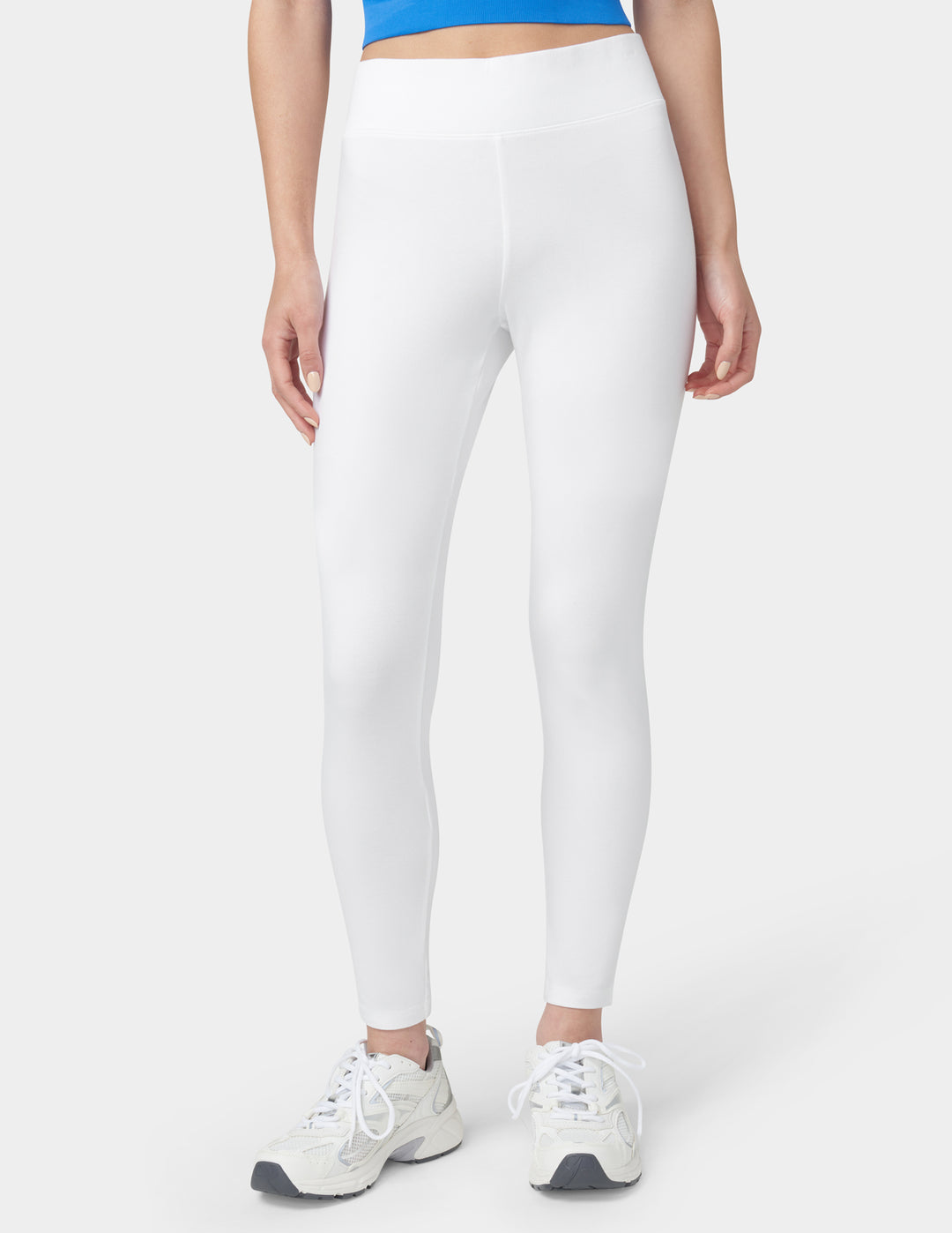 Person wearing white leggings and white sneakers on a white background