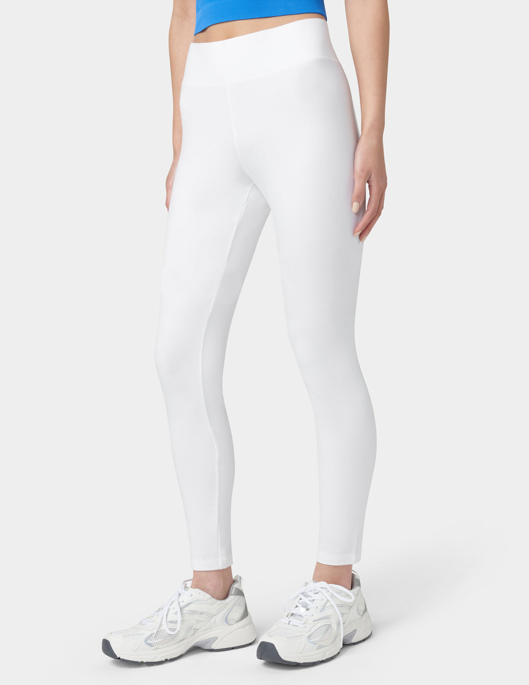 Person wearing white leggings and white sneakers on a white background