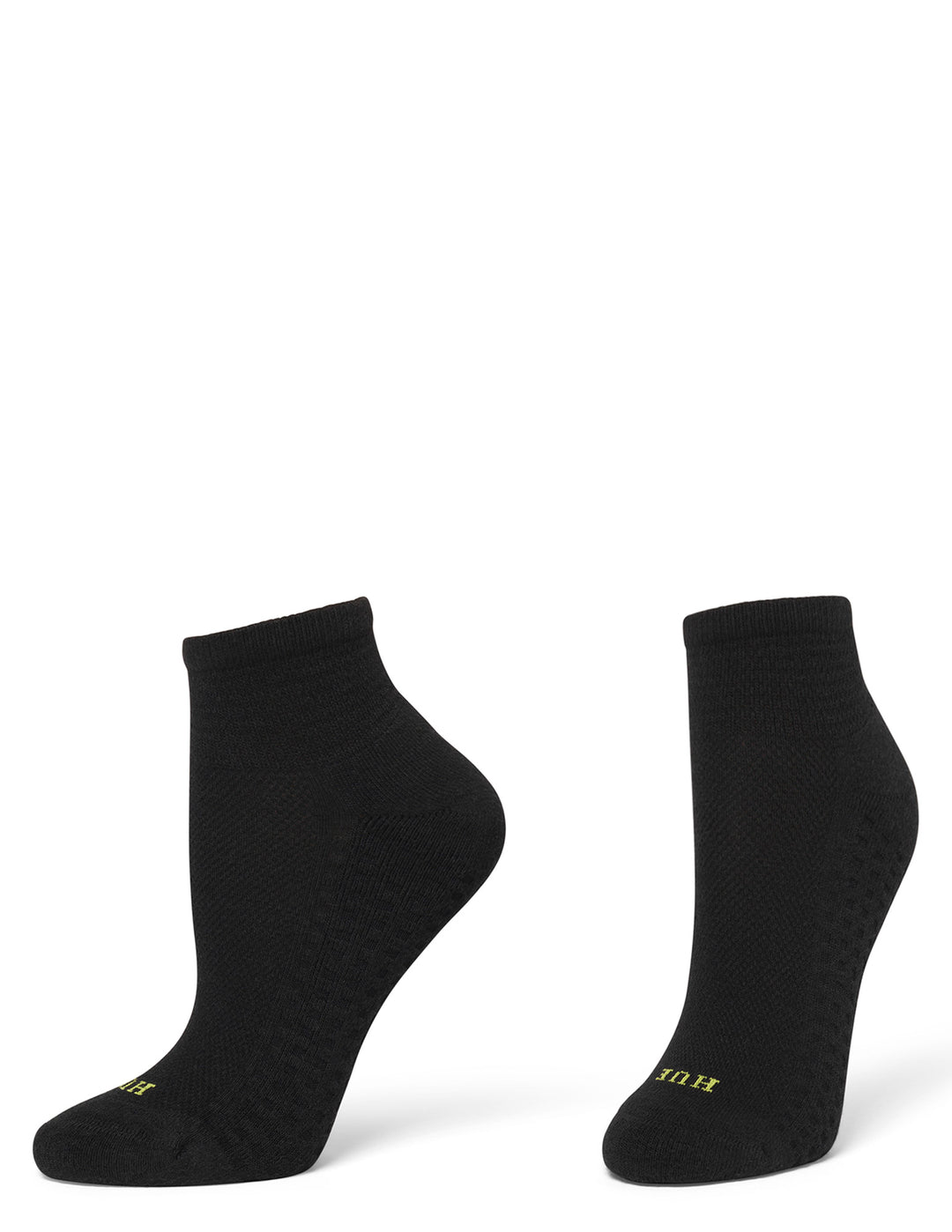 A pair of black low-cut athletic socks with a textured grip pattern and small yellow branding on the toes, displayed against a solid white background.