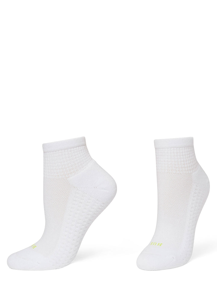 A pair of white low-cut athletic socks with textured knit patterns and small neon yellow branding near the toes, displayed on foot forms against a solid white background.