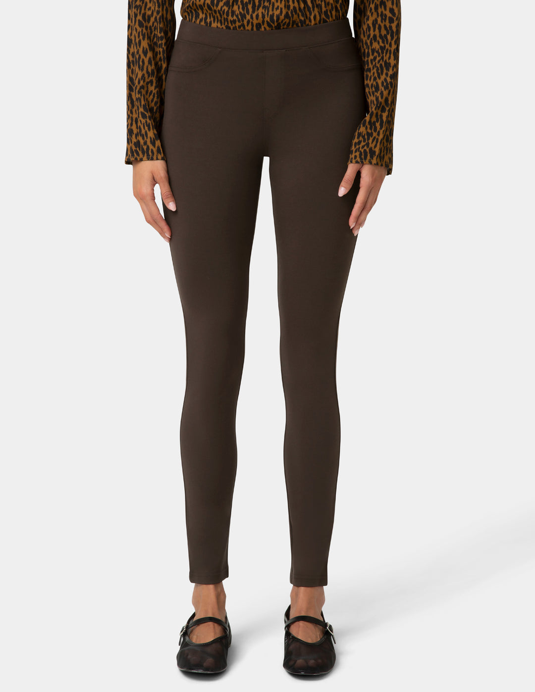 Brown leggings worn with a leopard print top on a white background