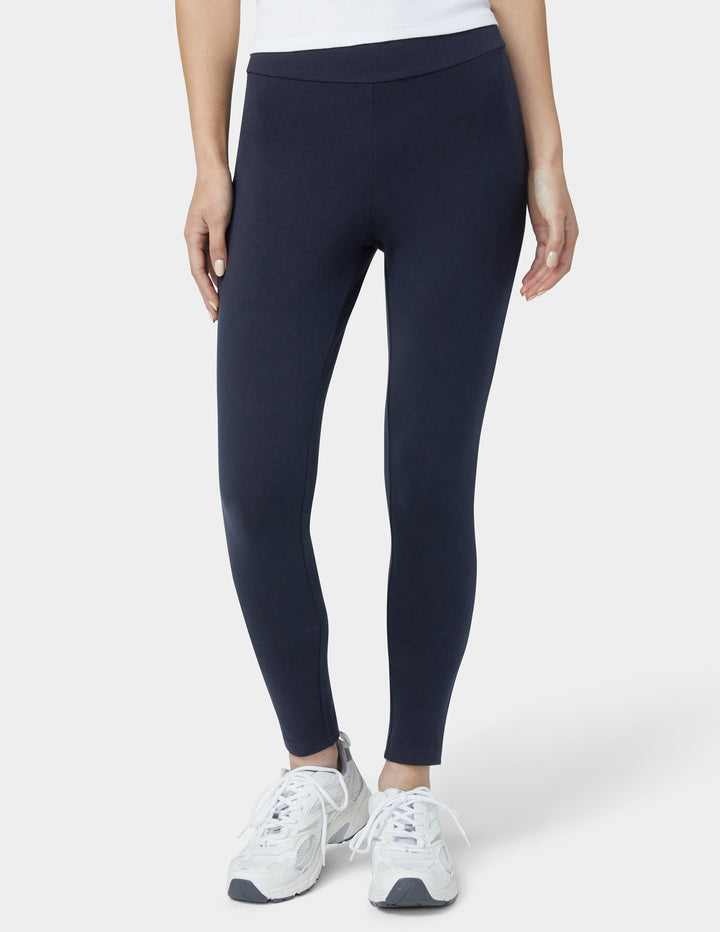 Person wearing navy leggings and white sneakers on a white background