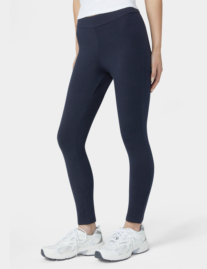 Person wearing navy leggings and white sneakers on a white background