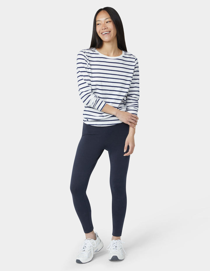 Woman wearing a striped long-sleeve shirt and dark leggings on a white background