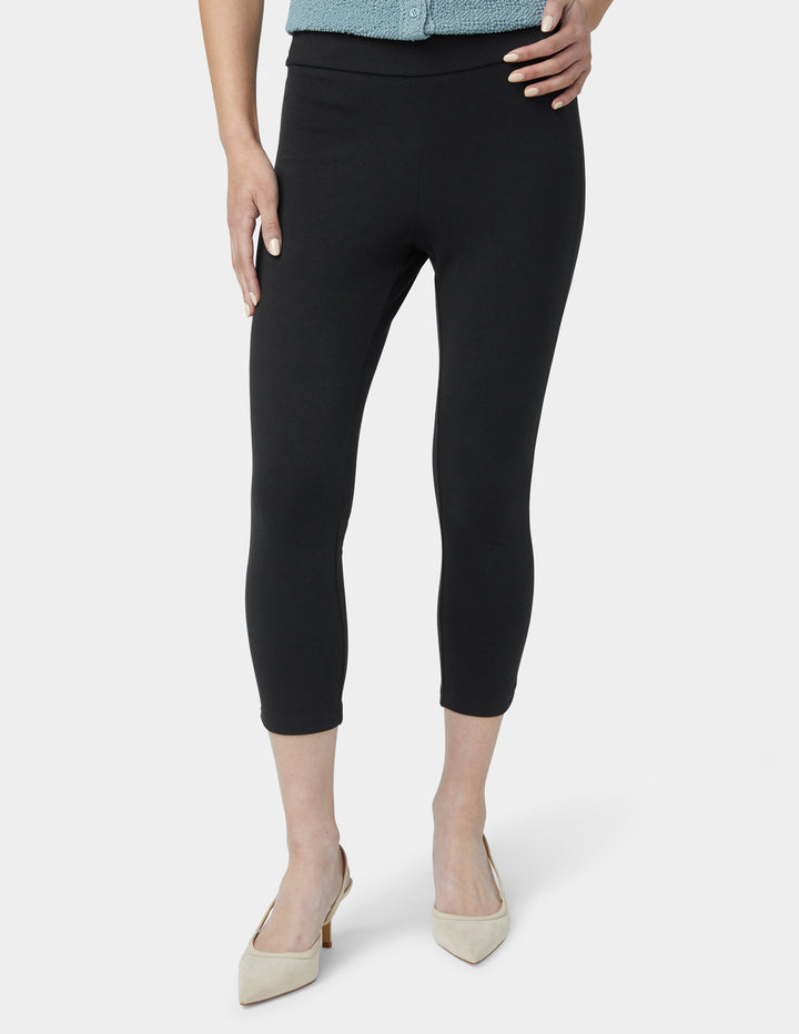 Person wearing black capri pants on a white background