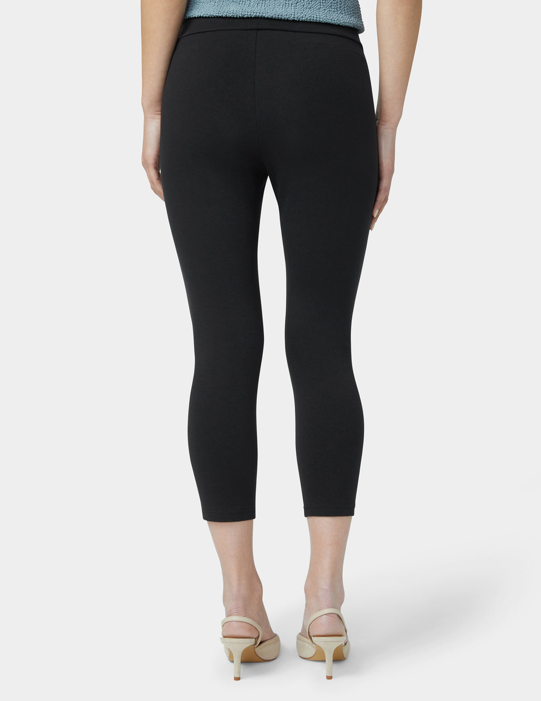 Person wearing black capri pants on a white background