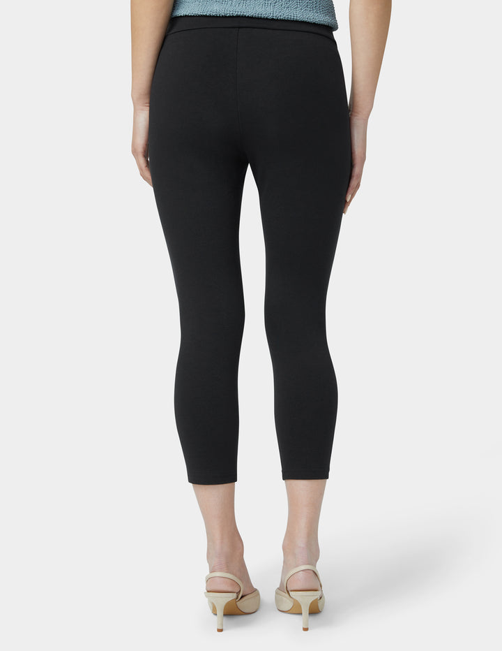 Person wearing black capri pants on a white background