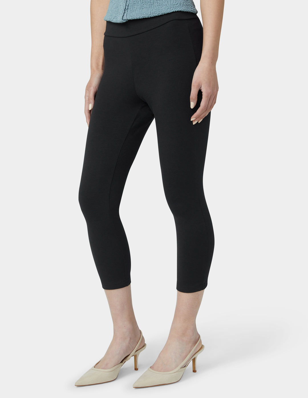 Person wearing black capri pants on a white background