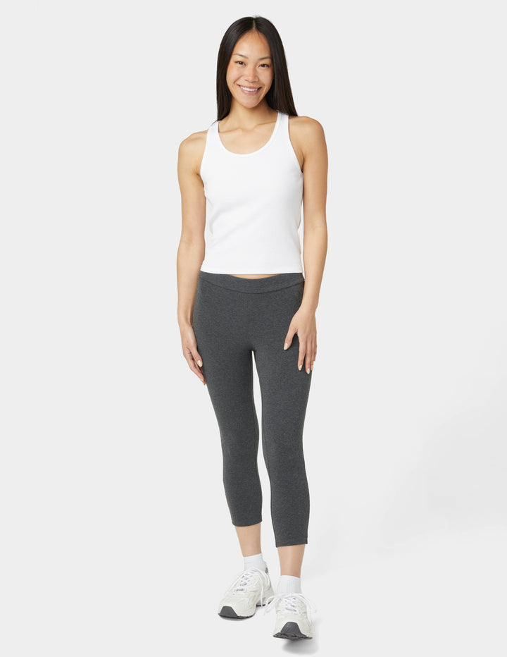 Woman wearing a white tank top and gray leggings on a white background