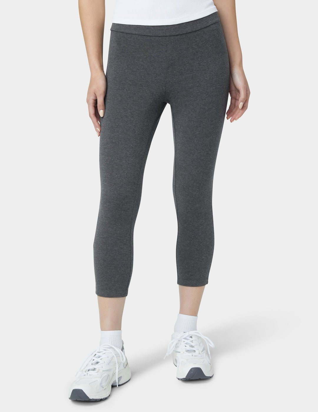 Person wearing gray leggings and white sneakers on a white background