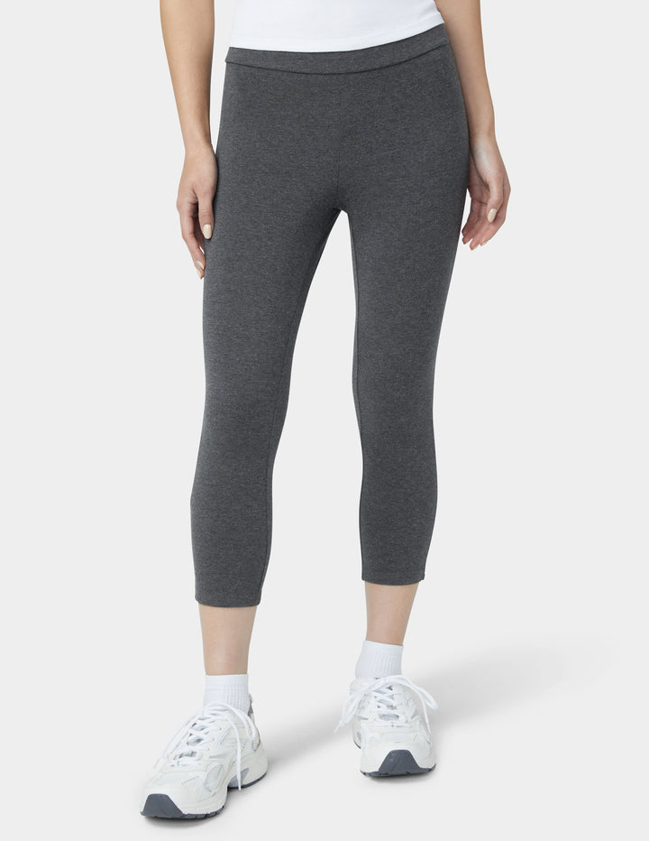 Person wearing gray leggings and white sneakers on a white background