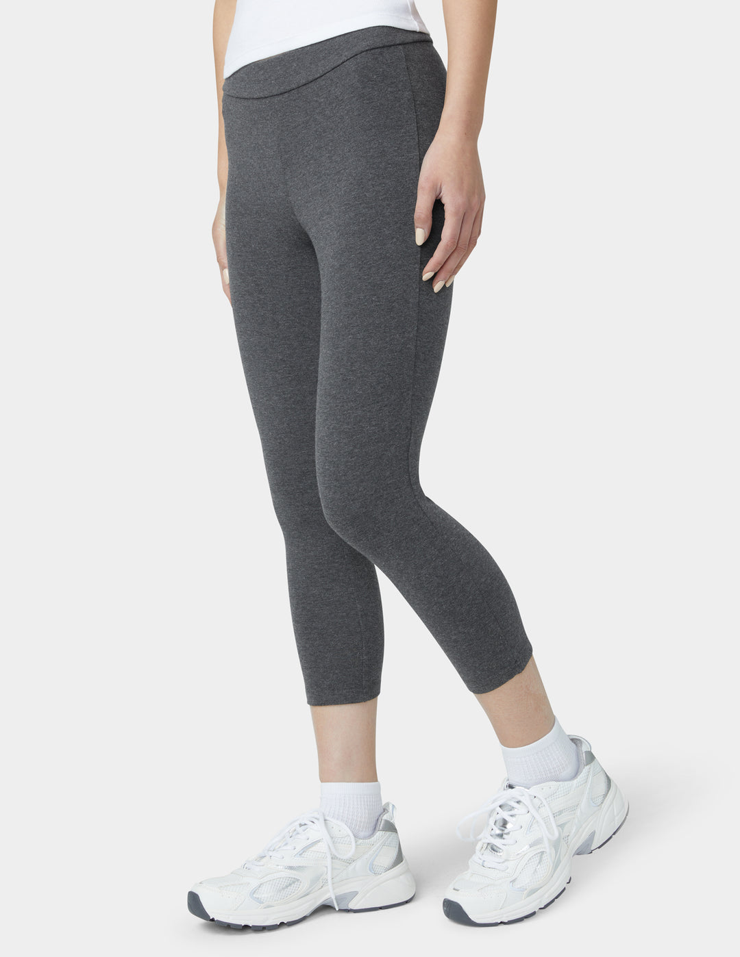 Person wearing gray leggings and white sneakers on a white background