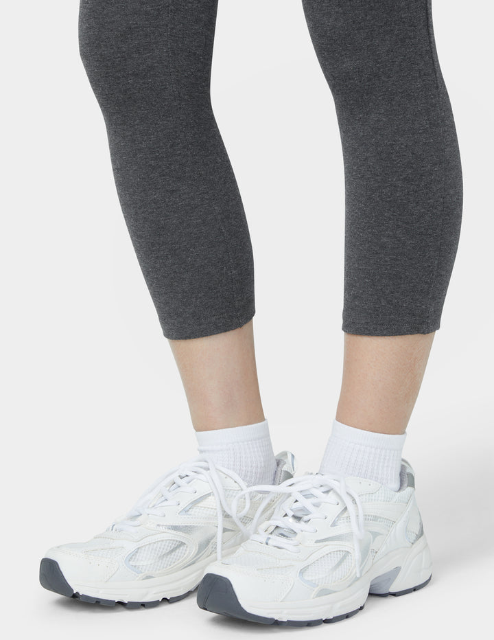 White sneakers worn with gray leggings on a light gray background