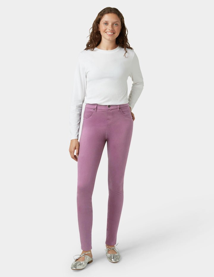 Woman wearing a white long-sleeve top and purple pants on a white background