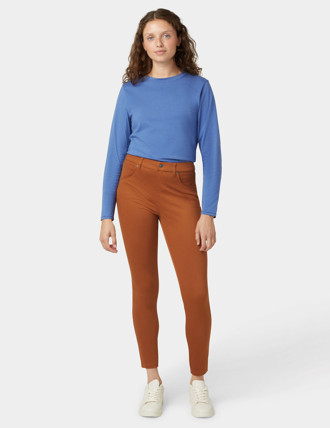 Woman wearing a blue top and brown pants on a white background