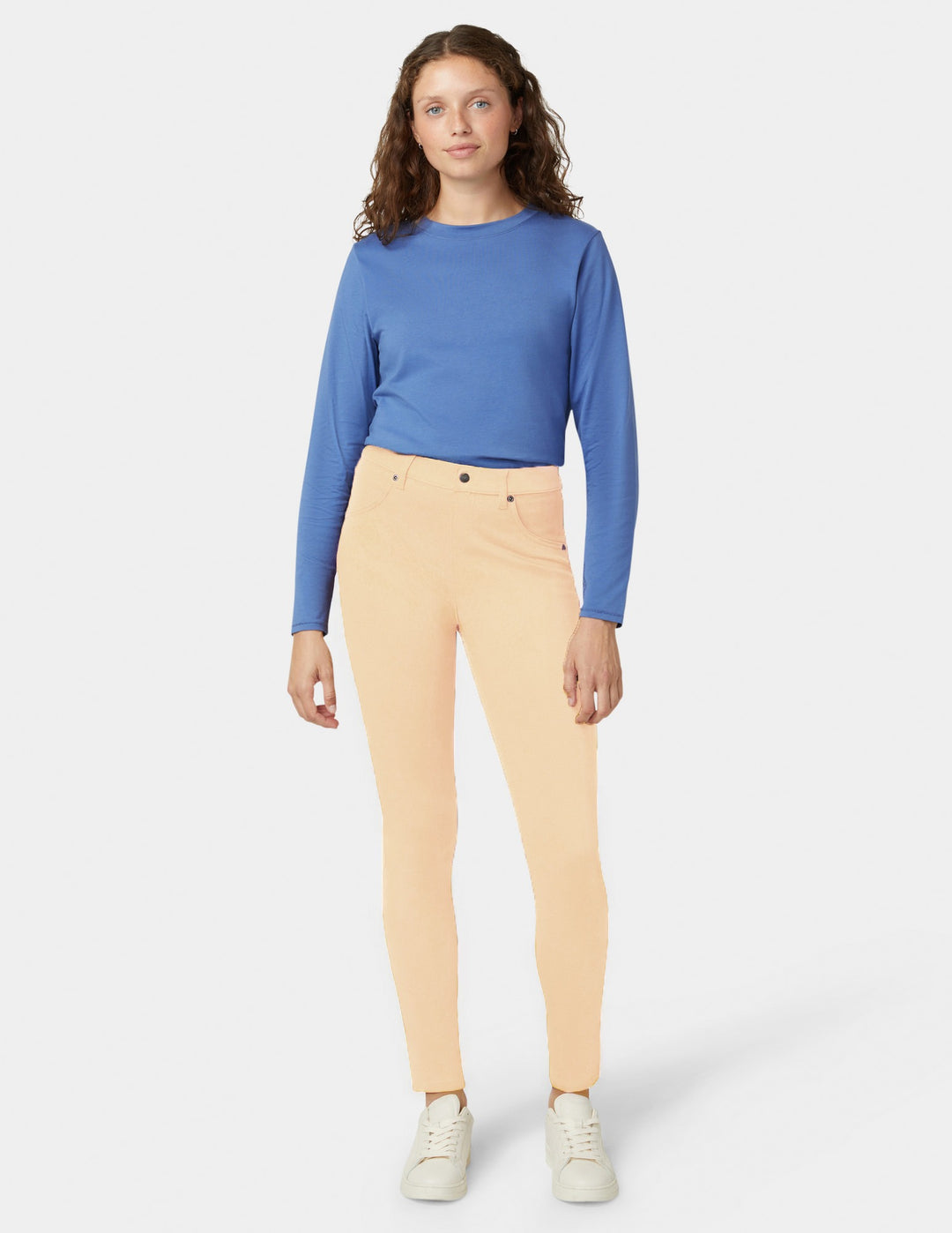 Yellow pants and blue top worn by a woman on a white background