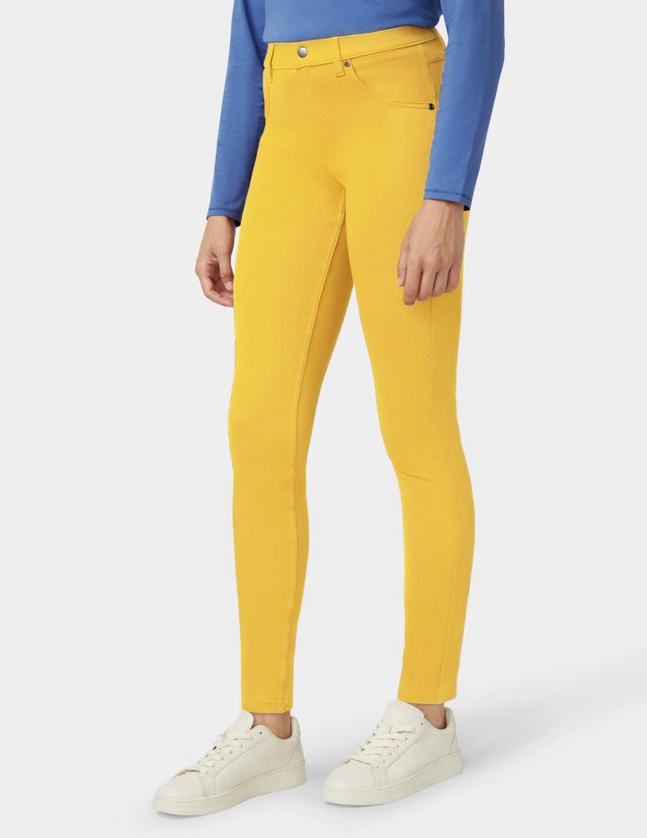 Person wearing mustard yellow pants with a blue top on a white background