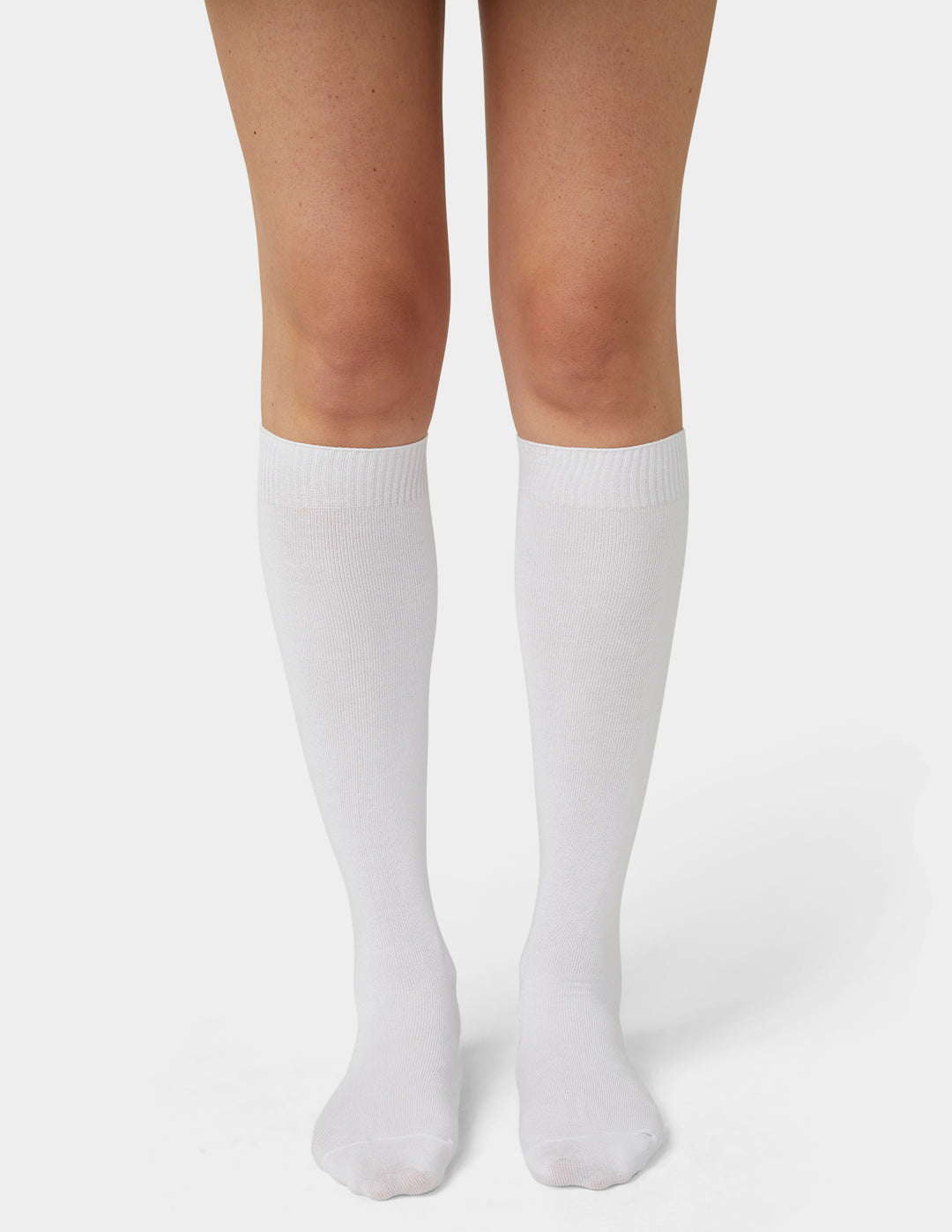 A pair of white knee-high socks worn on a model's legs, shown from the mid-thigh down against a clean light gray studio background.