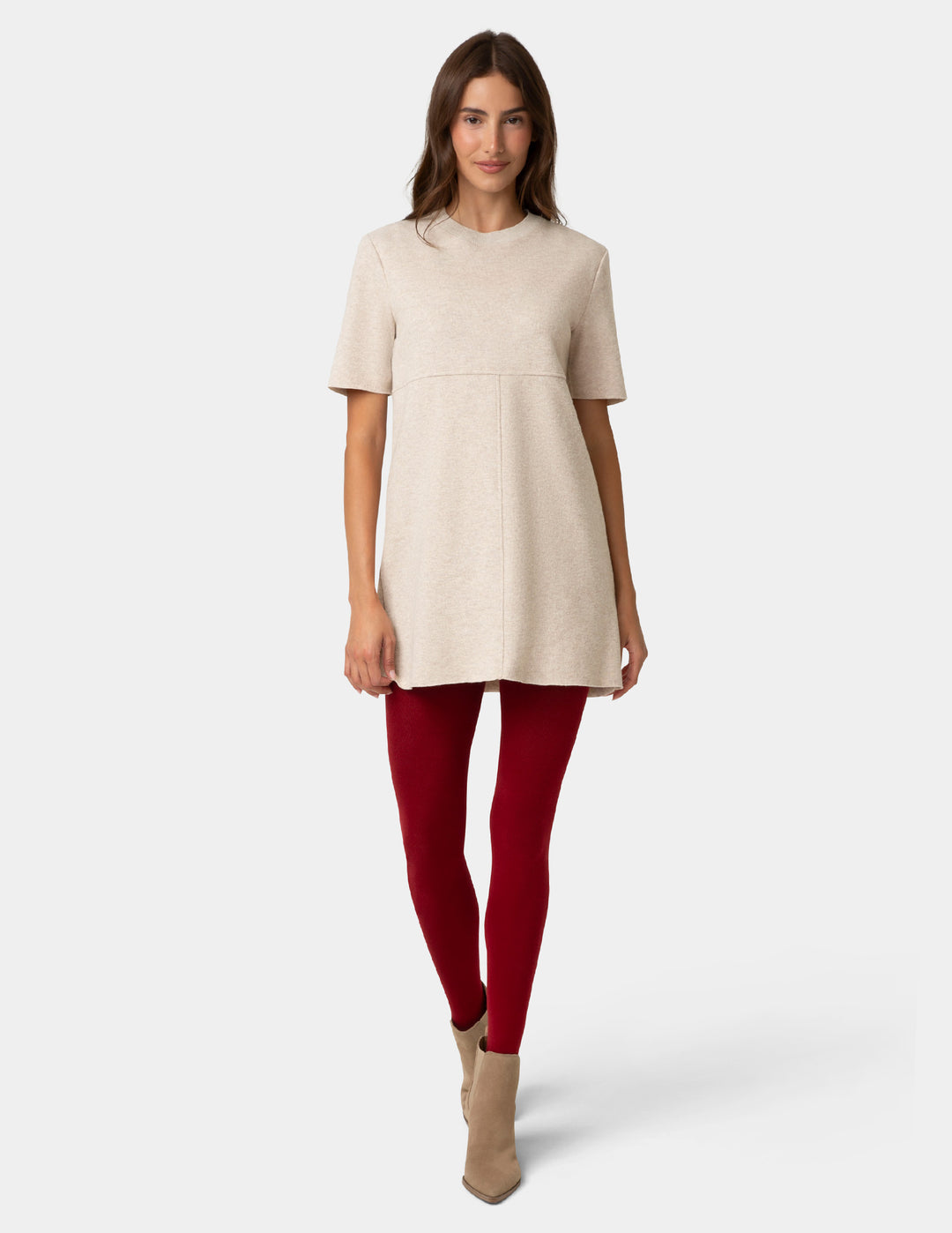 Woman wearing a beige dress and red knit tights on a white background