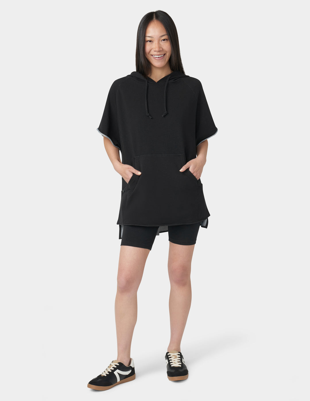 Person wearing a black hoodie and shorts set on a white background