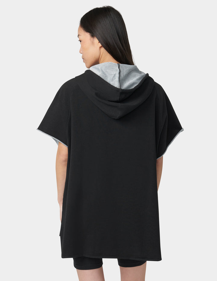 Person wearing a black hooded dress with gray lining on a white background