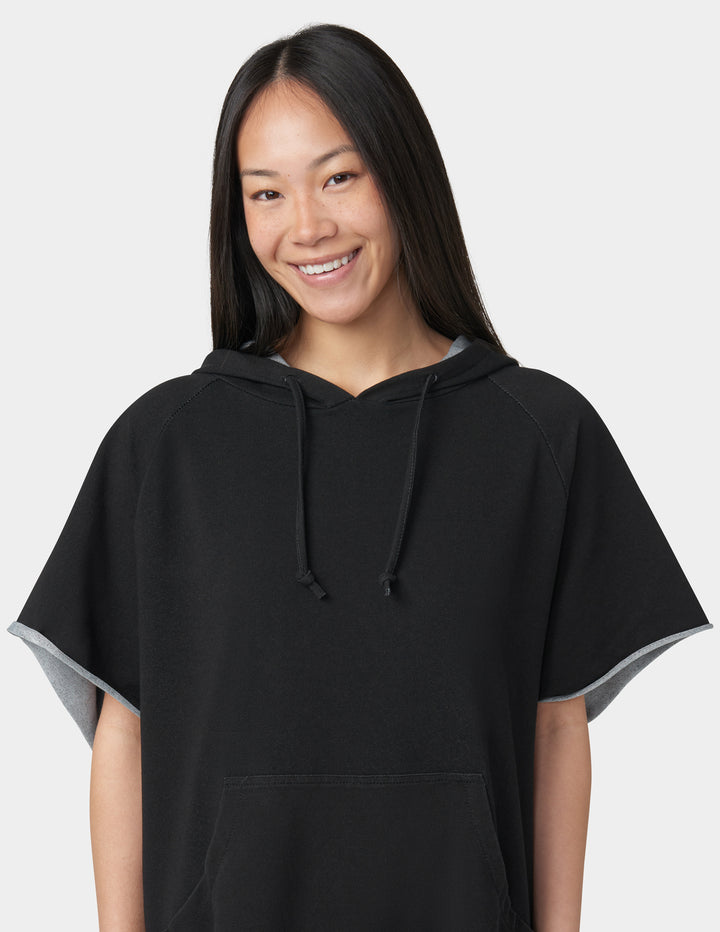 Person wearing a black hooded poncho against a white background