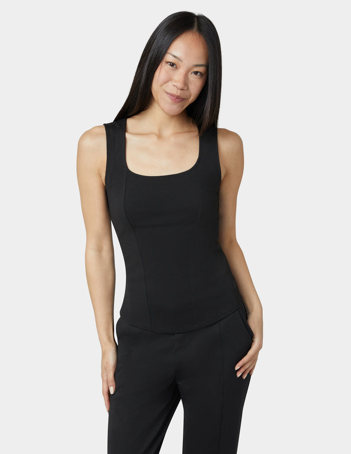 Woman wearing a black sleeveless top and pants on a white background