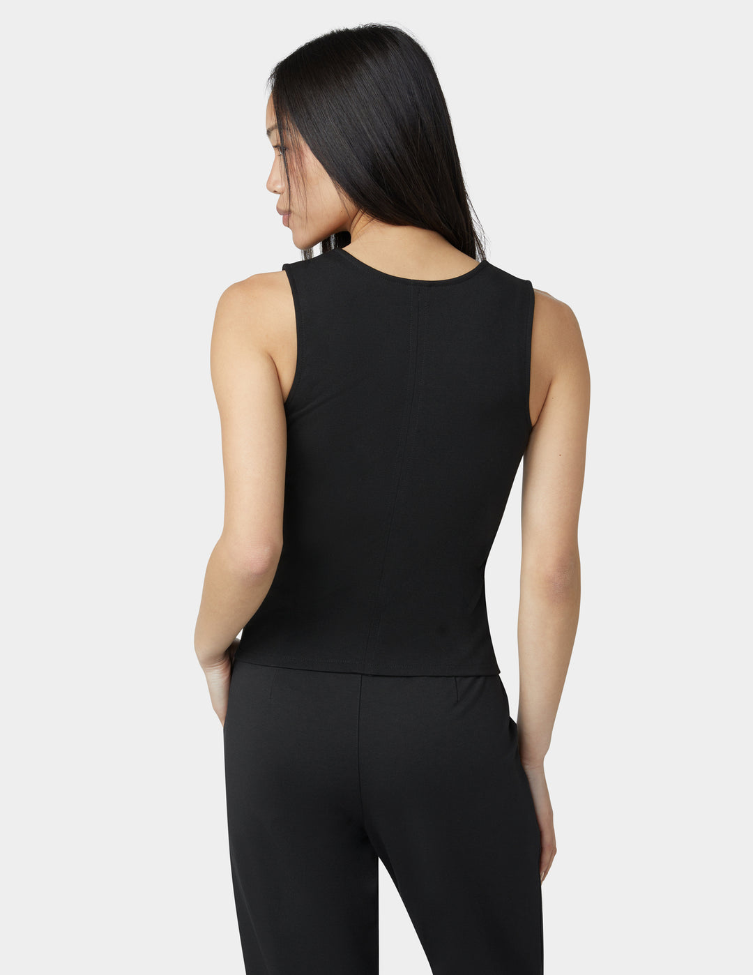 Woman wearing a black sleeveless top and pants on a white background