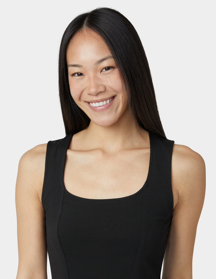 Woman wearing a black sleeveless top against a plain background
