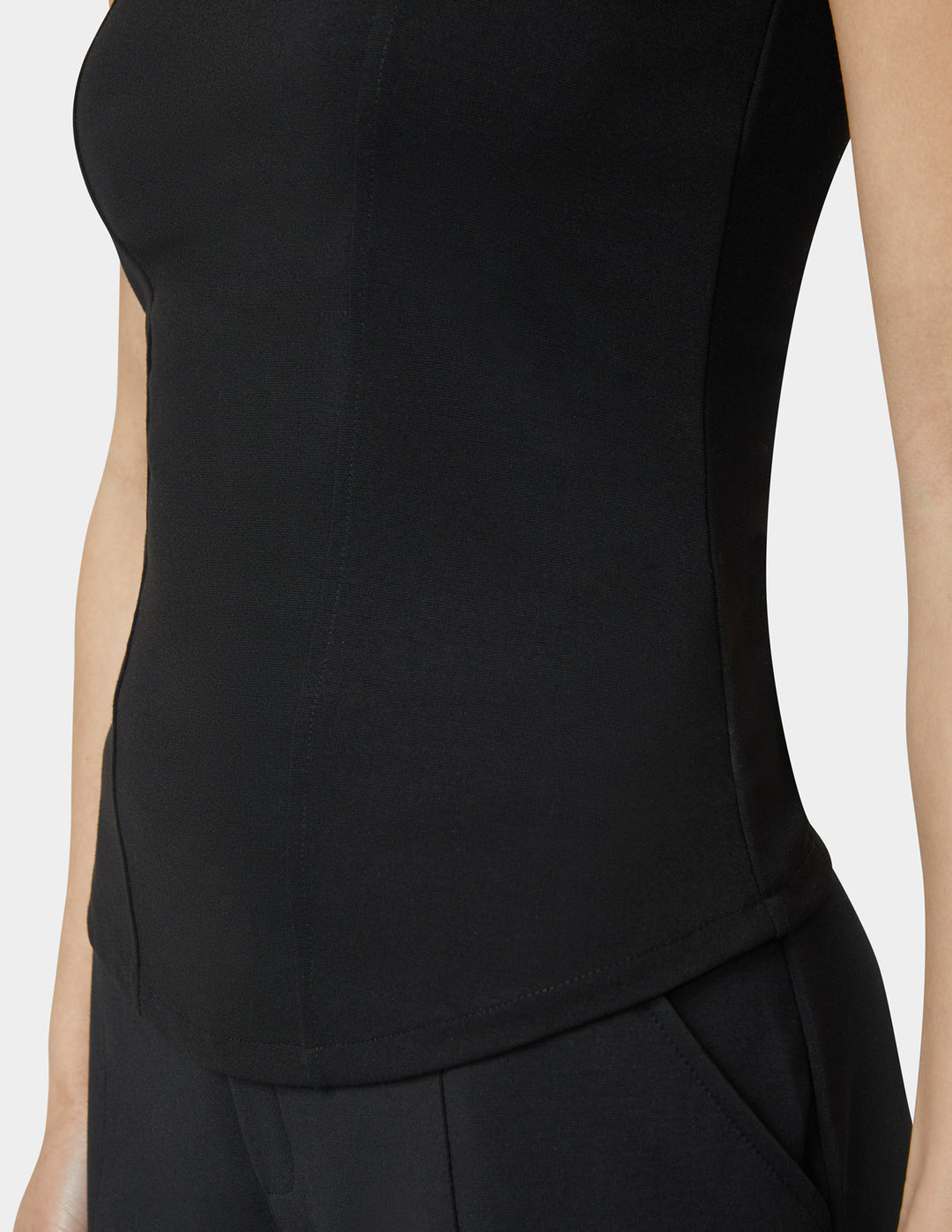 Black sleeveless top worn by a person on a white background