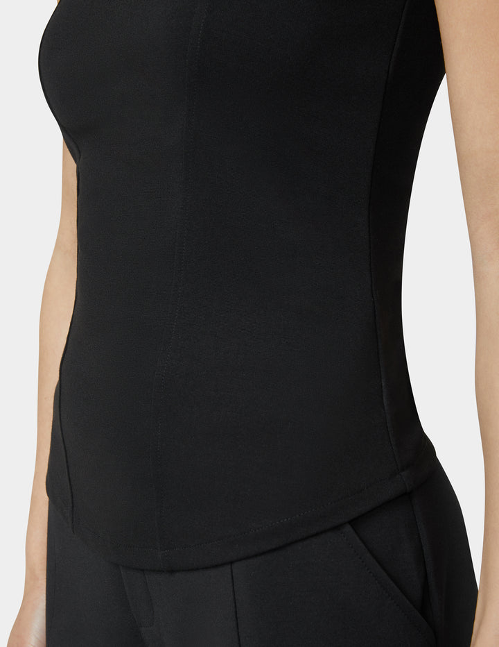 Black sleeveless top worn by a person on a white background