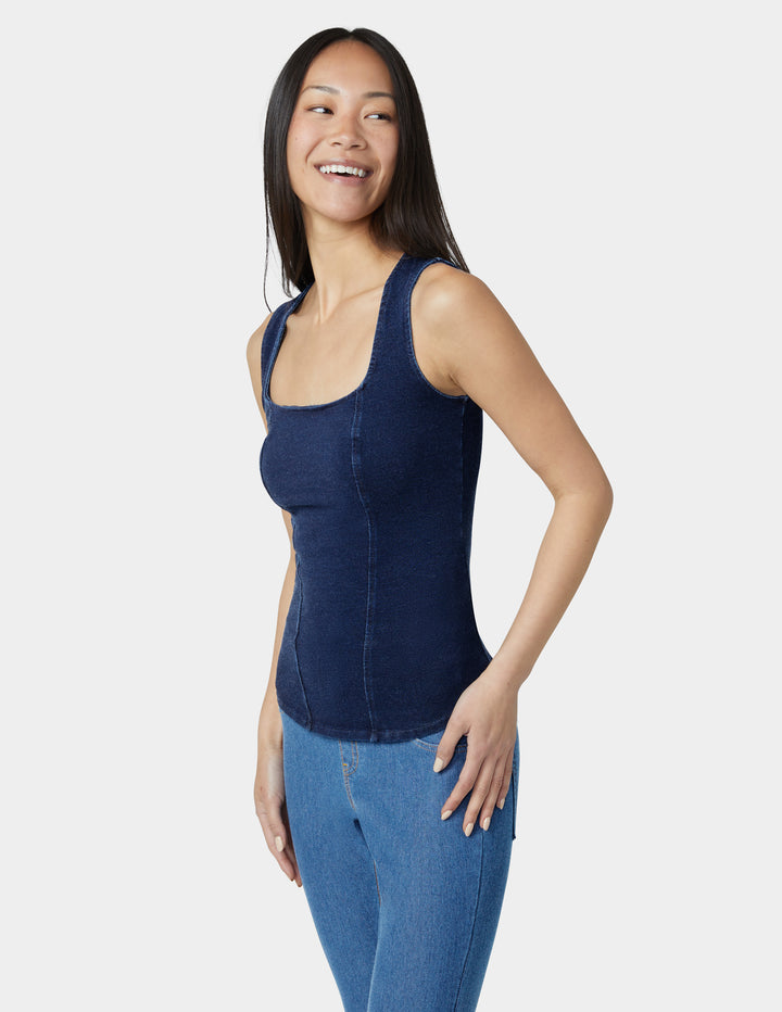 Woman wearing a navy tank top and blue jeans on a white background