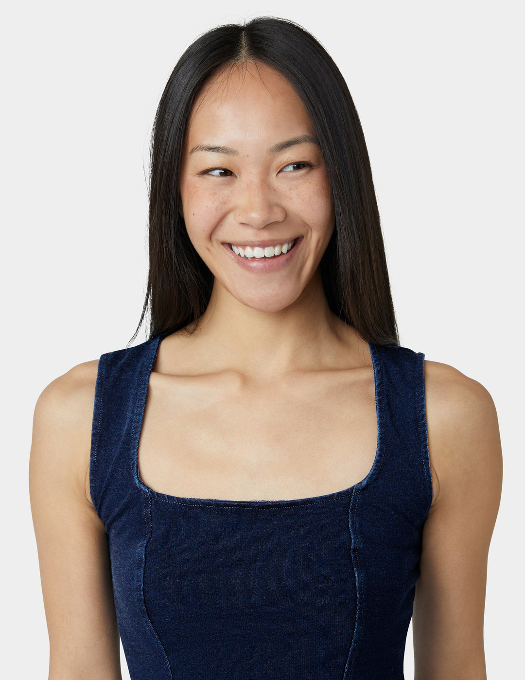 Woman wearing a navy blue sleeveless top against a white background