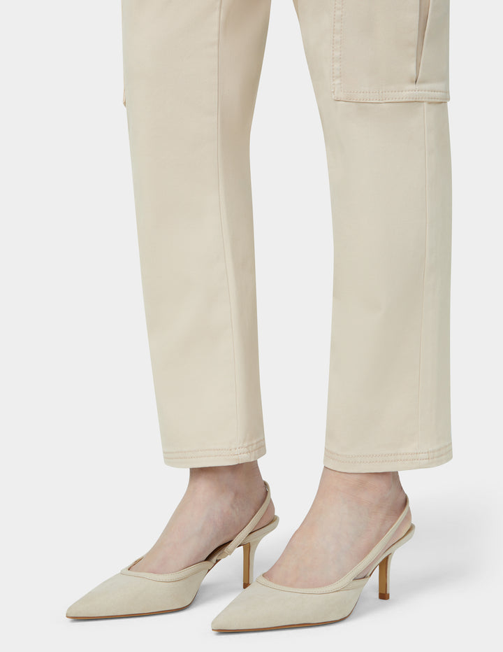 Beige high-heeled shoes worn with beige pants on a white background