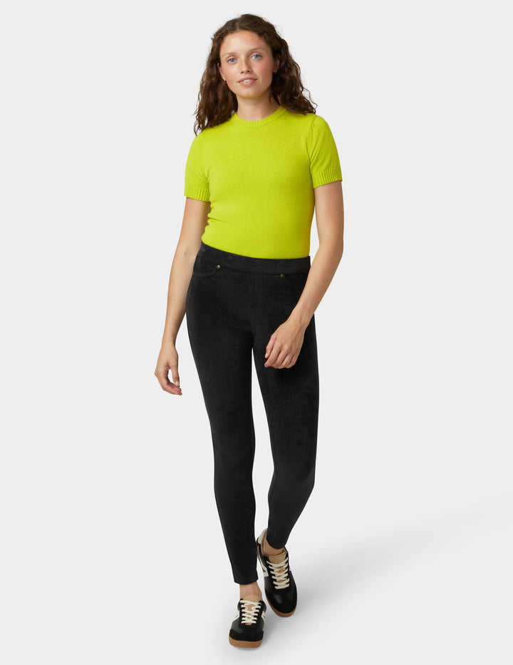 Person wearing a bright green shirt and black pants on a white background