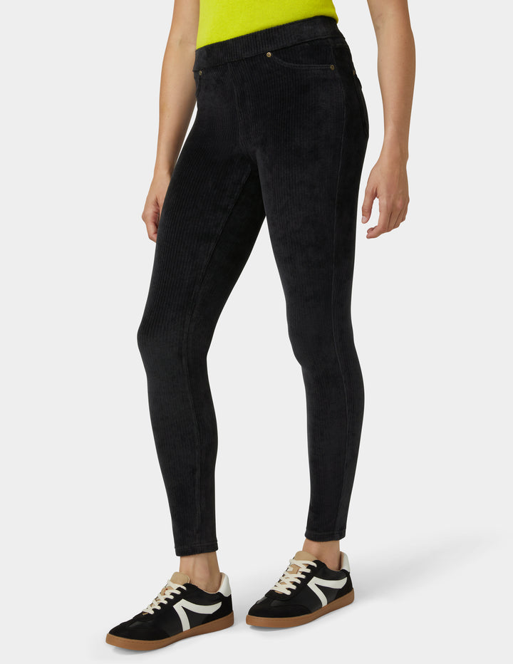 Person wearing black pants and black and white sneakers on a white background