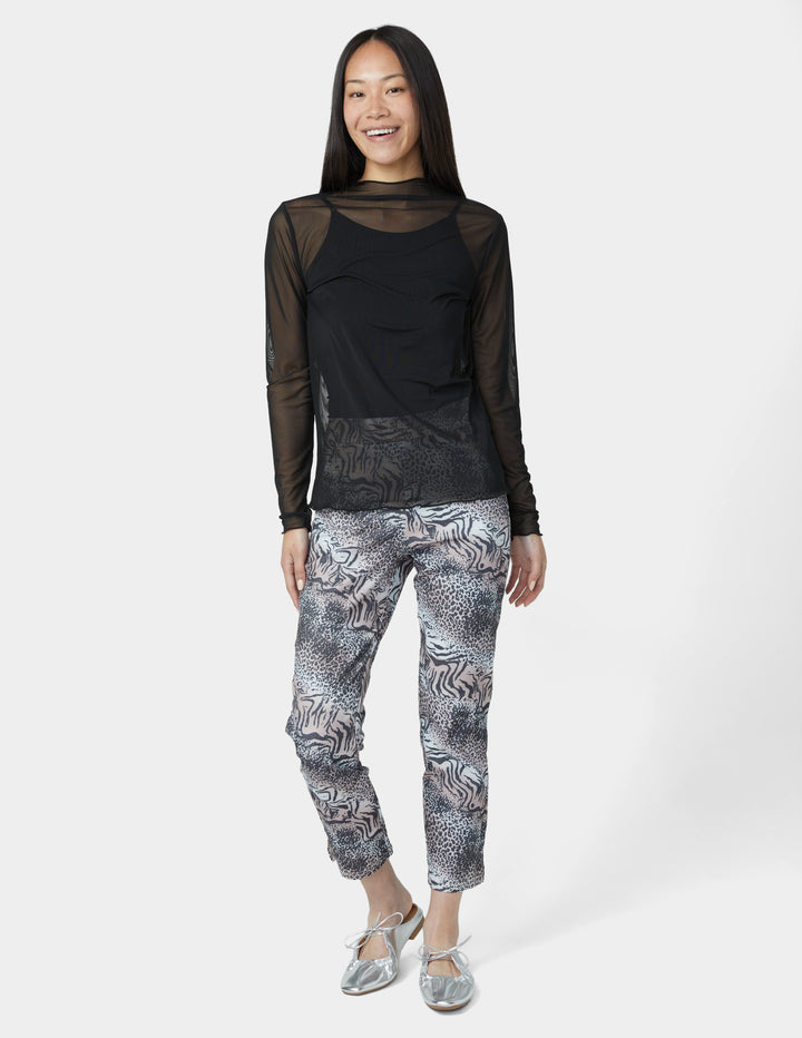 Woman wearing a black long-sleeve top and patterned pants on a white background