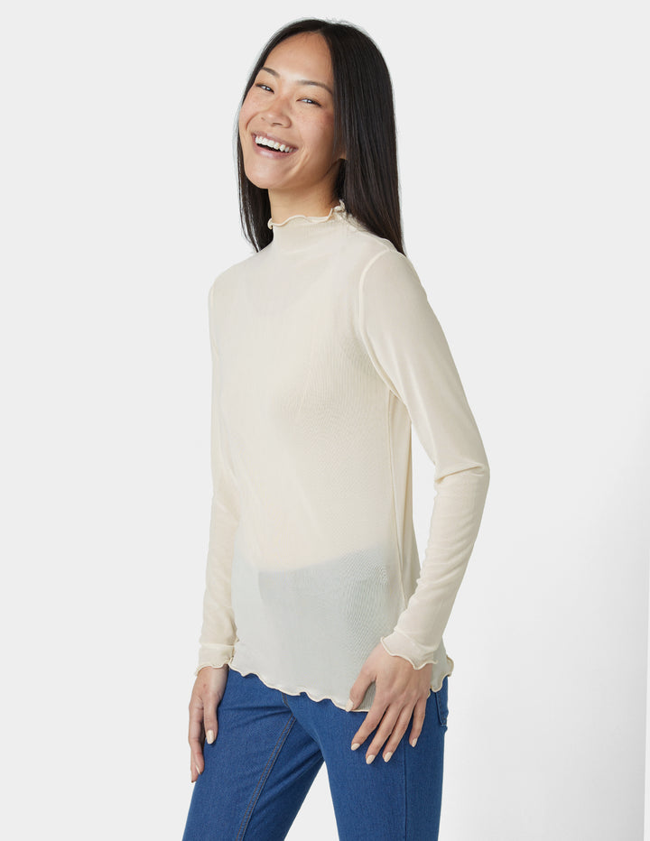 Woman wearing a cream long-sleeve top with a scalloped hem on a white background