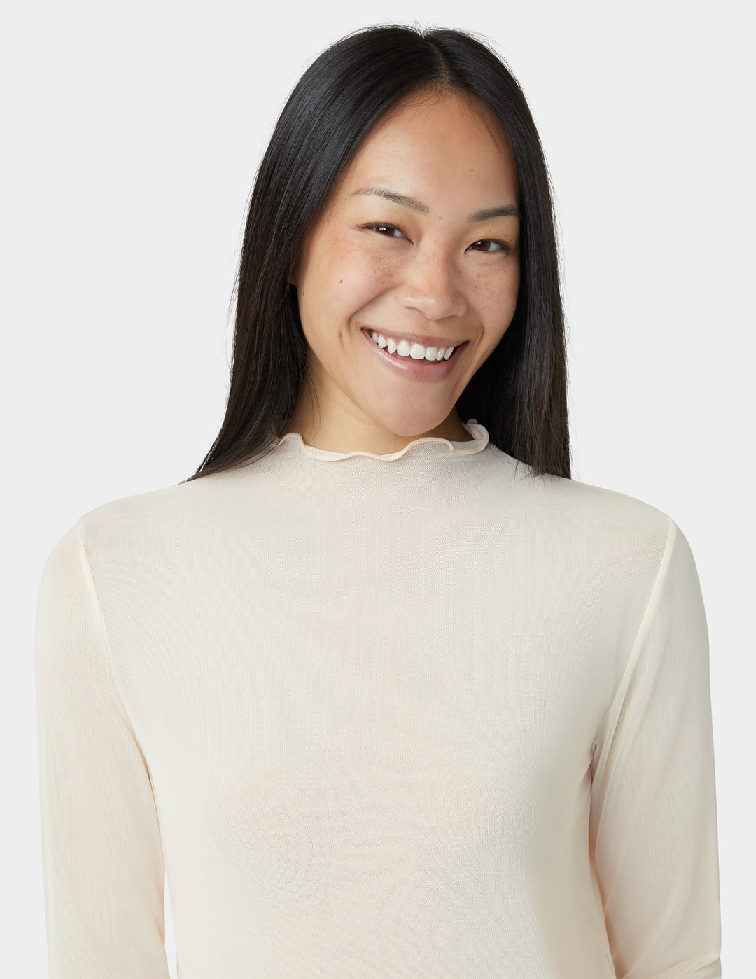 Woman wearing a beige long-sleeve top against a white background