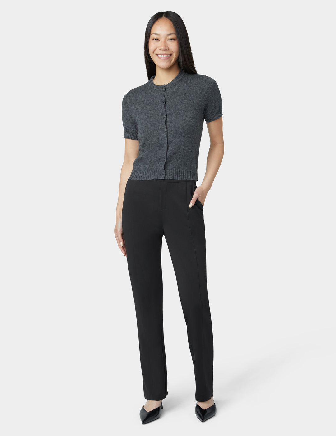 Woman wearing a gray short-sleeve cardigan and black pants on a white background